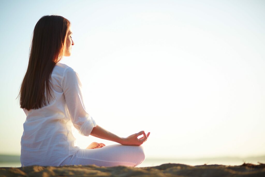 une femme en posture de lotus et est en train d'effectuer une méditation guidée
